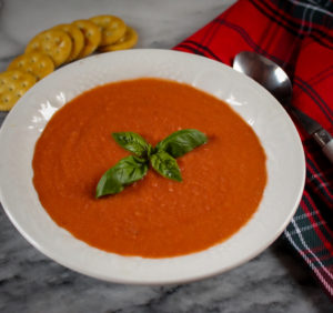 a bowl of vegan tomato soup with crackers
