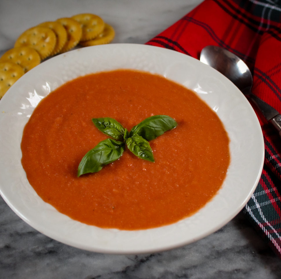 a bowl of vegan tomato soup with crackers